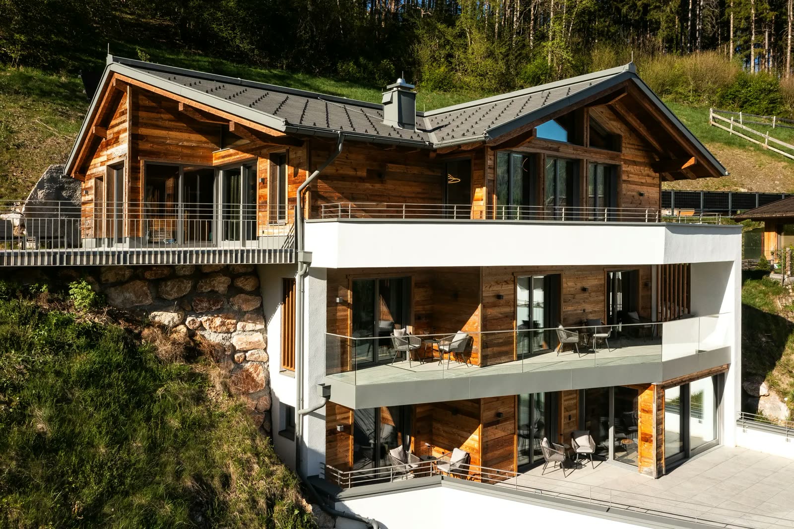 Modern wood and concrete chalet on a slope with terraces